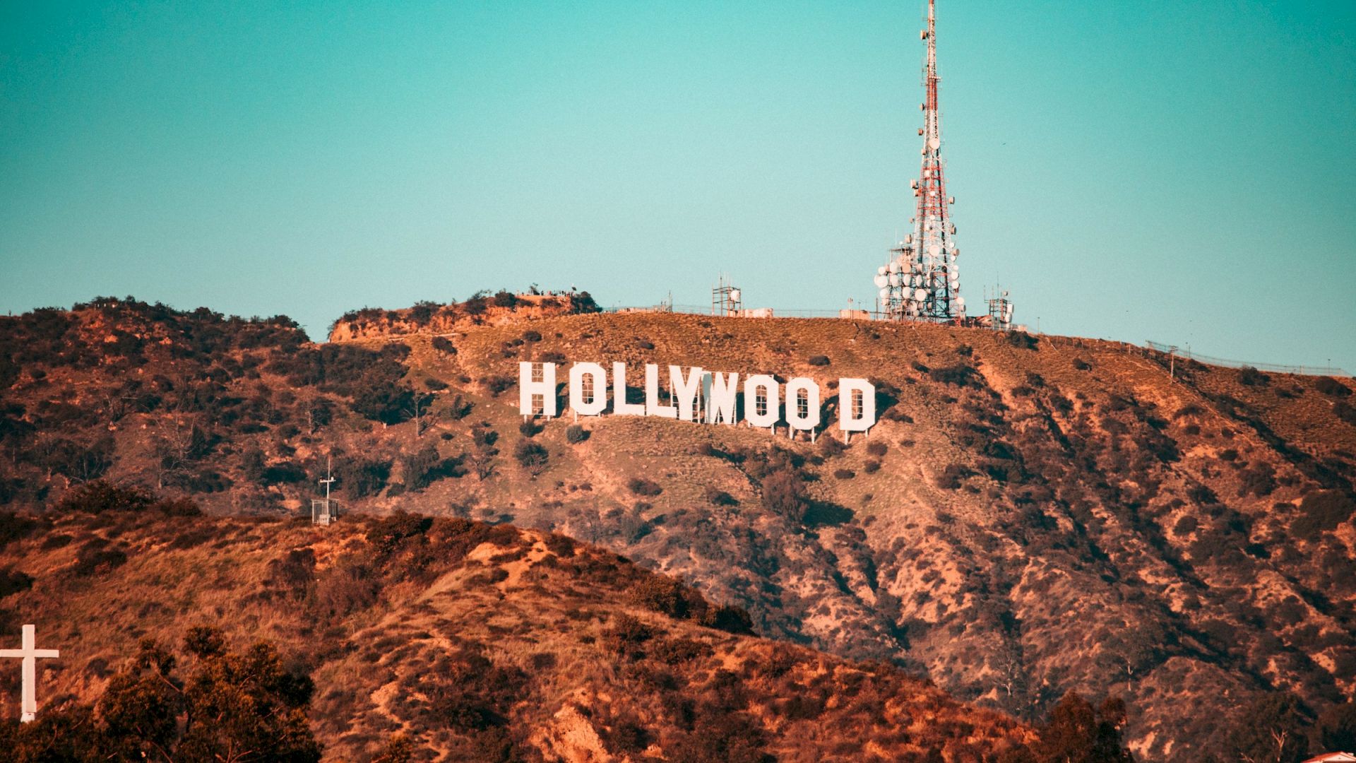 The image features the Hollywood Sign on a hillside, alongside a radio tower, set against a clear blue sky.