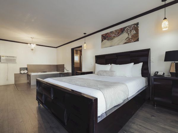 A modern bedroom with a large bed, elegant lamps, dark furniture, and a stylish painting above the bed, creating a cozy atmosphere.