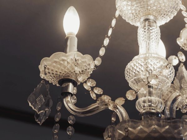 An ornate glass chandelier with lit bulbs and decorative crystal details hangs from the ceiling.