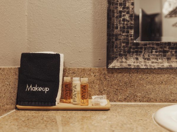 A bathroom counter with a makeup towel, toiletries, and a mirror.