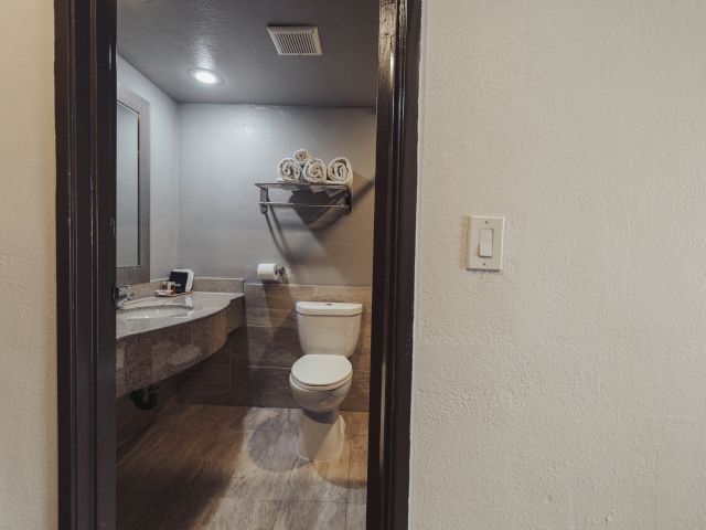 A standard hotel bathroom with a toilet, sink, and tiled walls